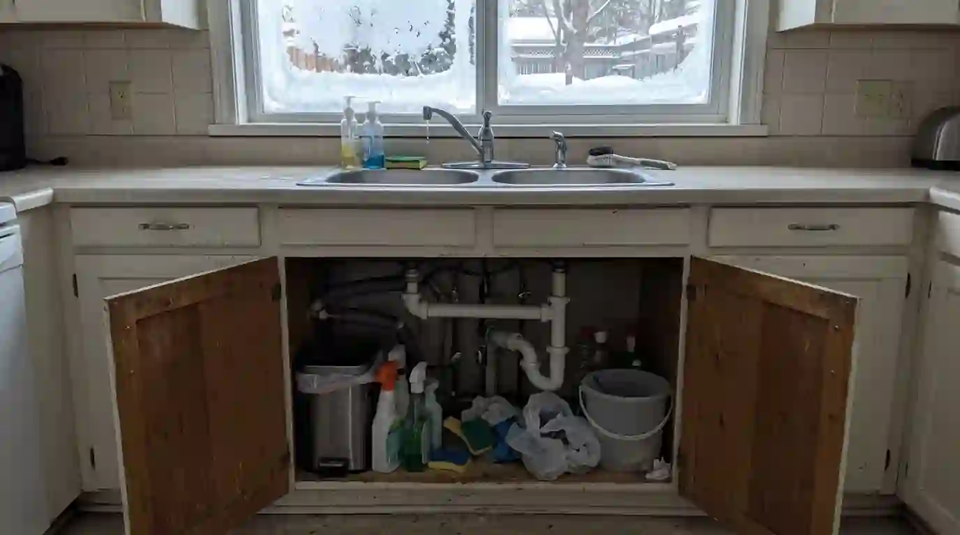 Cabinet doors opened under a sink on an outside wall during a freeze